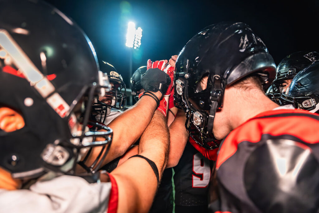 american football players huddling showing motivation and teamwork